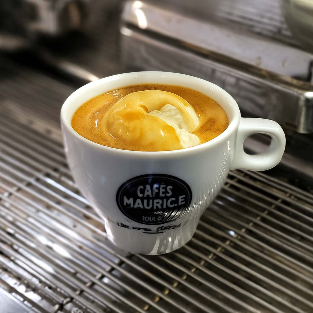 Tasse de café Affogato Cafés Maurice avec une boule de glace vanille fondant sous un expresso chaud, servie sur une machine à espresso.
